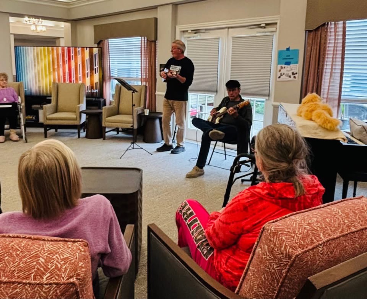 Jerry playing ukulele alongside a fellow musician for residents in a memory care community room