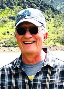 Jerry O'Neill smiling outdoors, wearing a cap and sunglasses.